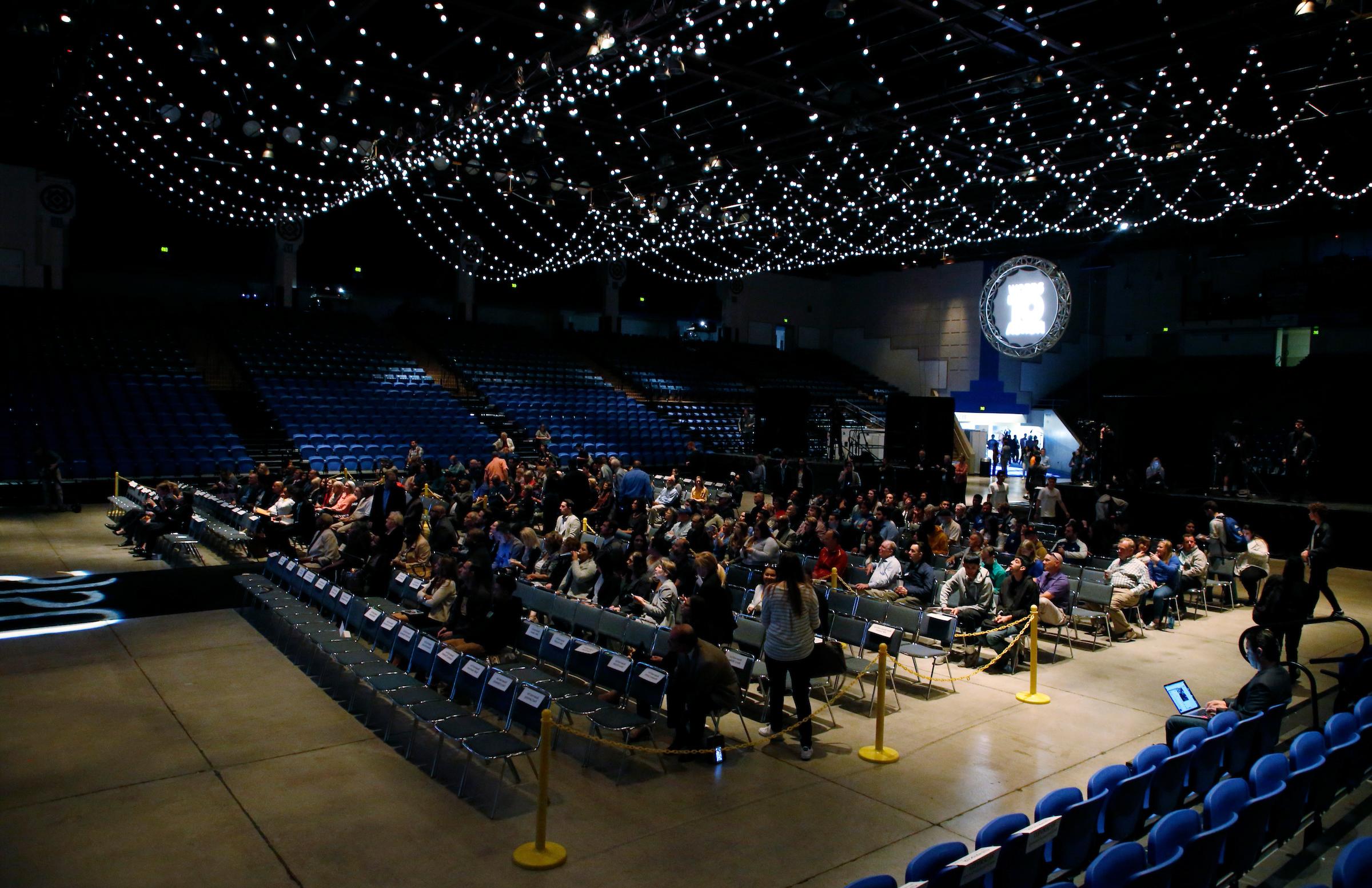 A crowd of people are seated inside a dark event center.