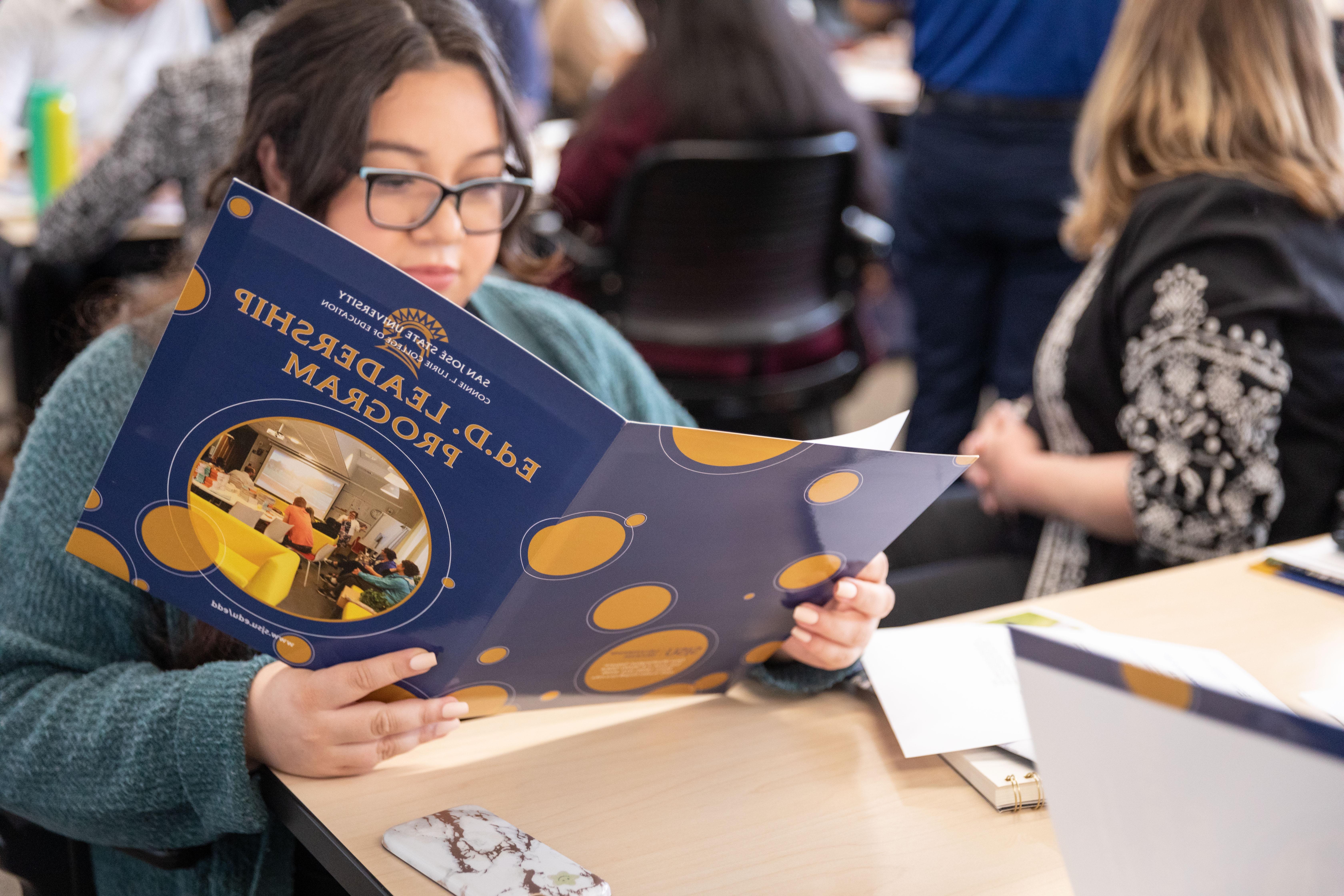 Student sits on table reading a binder