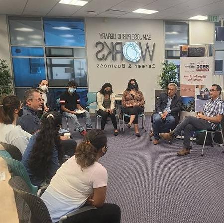 College students seated in a circle with a professor and a mentor discuss entrepreneurship.