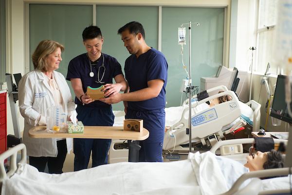 Two nursing students and a professor in a lab.