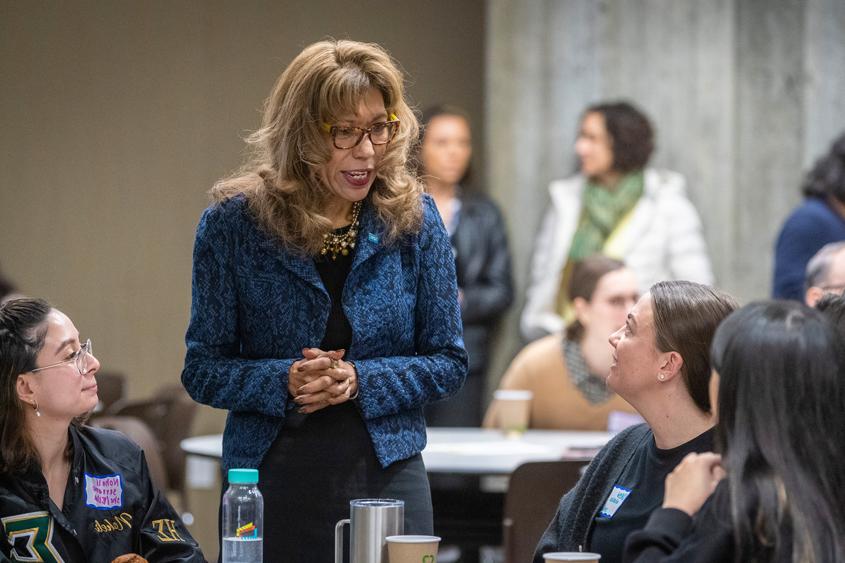 President Teniente-Matson speaking with students at a table.