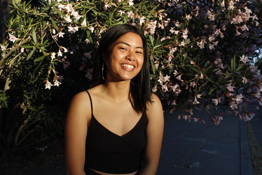 Marielle Lacanlale posing in front of a flower wall.